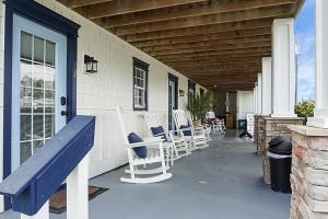 eine Veranda mit weißen Schaukelstühlen auf einem Haus in der Unterkunft Carolina Beach Inn in Carolina Beach