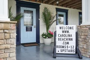 una señal de bienvenida frente a una casa con puerta en Carolina Beach Inn, en Carolina Beach