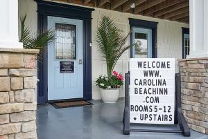a welcome sign in front of a house with a door at Carolina Beach Inn in Carolina Beach