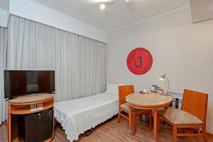 a room with a bed and a table and a tv at Slaviero São Paulo Moema in Sao Paulo