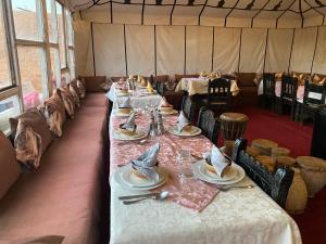 メルズーガにあるMerzouga Luxury Campsのテント内の長テーブル(皿、ナプキン付)