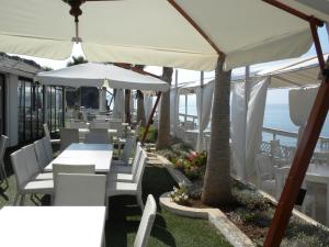 a restaurant with white tables and white chairs and the ocean at Baia Santa Maria in Cittadella del Capo