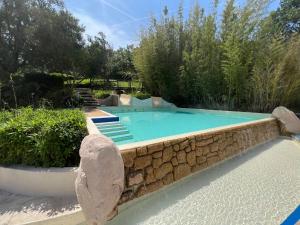 a swimming pool with a stone wall around it at AZUR APPARTEMENT (SEA VIEW) LES RESTANQUES DE ST-TROPEZ1131 in Grimaud