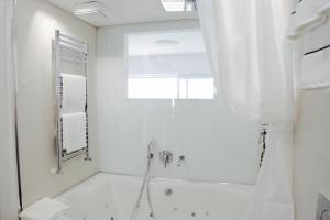 ein weißes Bad mit einer Badewanne und einem Spiegel in der Unterkunft "Fall in love only" Morcote lake in Morcote