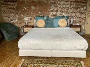 een slaapkamer met een groot bed met een bakstenen muur bij La Cure de Noduwez in Noduwez