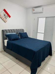 1 dormitorio con cama con sábanas azules y ventana en APARTAMENTO AMPLO COMPLETO (SUITE/QUARTO), en Americana