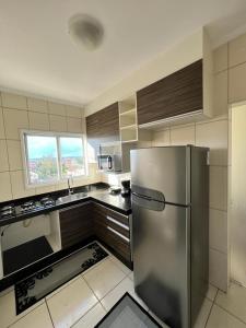 cocina con nevera de acero inoxidable y ventana en APARTAMENTO AMPLO COMPLETO (SUITE/QUARTO), en Americana