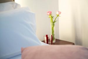 バルセロナにあるHotel Casa Trafalgar Barcelonaのベッド横のテーブルの上の花瓶のピンクのバラ2本