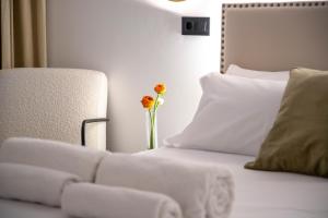 a white bed with two orange flowers in a vase at Hotel Casa Trafalgar Barcelona in Barcelona