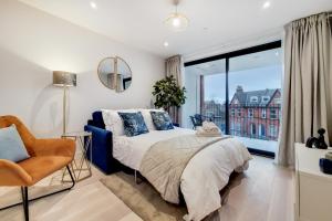 a bedroom with a bed and a window and a chair at Deluxe Harrow Wembley Apartment in Harrow
