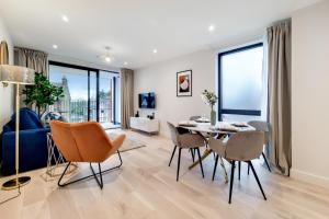 a living room with a dining room table and chairs at Deluxe Harrow Wembley Apartment in Harrow