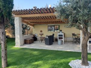 a backyard with a patio with a wooden pergola at La Maison 1440 in LʼIsle-sur-la-Sorgue