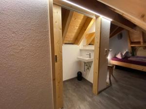 una puerta abierta a una habitación con lavabo y cama en Ferienbauernhof-Holops en Sankt Georgen im Schwarzwald