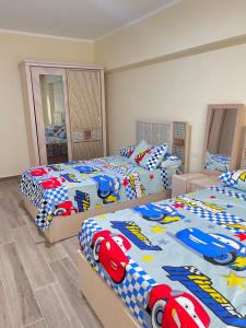 sypialnia z 3 łóżkami z wyścigowymi samochodami w obiekcie 2BD Apartment In New Alamein City شقة فندقية مدينة العلمين الجديدة w mieście El Alamein