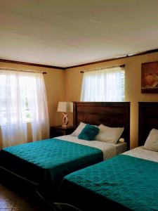 a bedroom with two beds and two windows at Eden Crest Villa in Anse La Raye