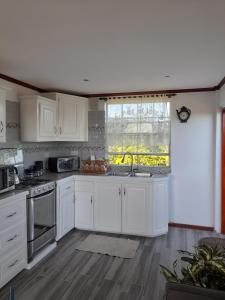 a kitchen with white cabinets and a large window at Eden Crest Villa in Anse La Raye
