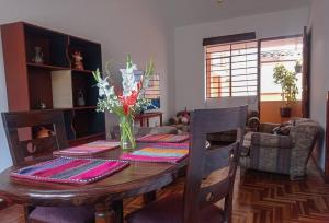 a dining room table with a vase of flowers on it at APARTAMENTO URMA Cuzco in Cusco