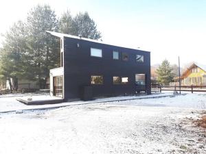 Ein schwarzes Haus, das auf einem schneebedeckten Hof steht. in der Unterkunft Refugio de montaña en pleno centro Malalcahuello. in Malalcahuello + 10 Fotos