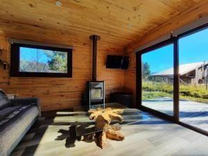 ein Wohnzimmer mit einem Glastisch in einer Blockhütte in der Unterkunft Refugio de montaña en pleno centro Malalcahuello. in Malalcahuello