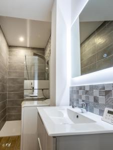 ein weißes Badezimmer mit einem Waschbecken und einem Spiegel in der Unterkunft LE VIEUX LAVAL in Laval