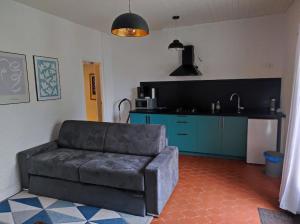 a living room with a couch and a kitchen at gîte 2 à 4 personnes (SPA, Sauna, piscine chauffée) in Saint-Vivien