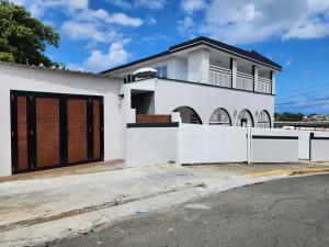 ein weißes Haus mit einem Tor und einem Zaun in der Unterkunft Casa Delizia close to everywhere! in San Juan