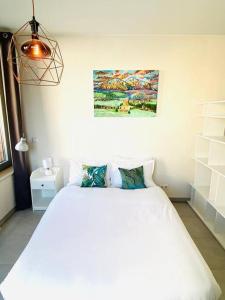 een slaapkamer met een wit bed en een schilderij aan de muur bij Large Studio in Center with Terrace. 1 min walk to the Tram. Cosy in Luxemburg
