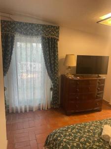 ein Schlafzimmer mit einem Bett und einer Kommode mit einem Fernseher in der Unterkunft DIMORA DISIU - Jacuzzi & Sea View - 4 minuti a piedi dal centro in Taormina