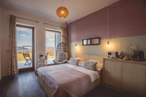 a bedroom with a large bed and a balcony at Natura Hill Panzió & Slow Food Fine Bistro in Zebegény