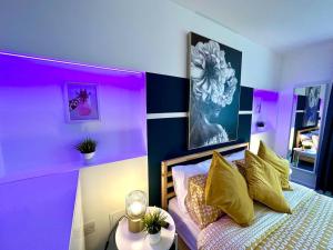 ein lila Schlafzimmer mit einem Bett mit gelben Kissen und einem Tisch in der Unterkunft Massive New 8 bedroom House Sleeps up to 21 - Accepts Groups - Great Location - FREE Parking - Fast WiFi - Smart TVs - sleeps up to 21 people - Close to Bournemouth & Poole Town Centre & Sandbanks in Bournemouth