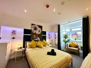 um quarto com uma cama grande e almofadas amarelas em Massive New 8 bedroom House Sleeps up to 21 - Accepts Groups - Great Location - FREE Parking - Fast WiFi - Smart TVs - sleeps up to 21 people - Close to Bournemouth & Poole Town Centre & Sandbanks em Bournemouth