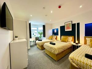 ボーンマスにあるMassive New 8 bedroom House Sleeps up to 21 - Accepts Groups - Great Location - FREE Parking - Fast WiFi - Smart TVs - sleeps up to 21 people - Close to Bournemouth & Poole Town Centre & Sandbanksのベッド2台、薄型テレビが備わるホテルルームです。