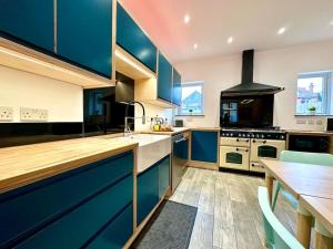 cocina con armarios azules y encimera de madera en Massive New 8 bedroom House Sleeps up to 21 - Accepts Groups - Great Location - FREE Parking - Fast WiFi - Smart TVs - sleeps up to 21 people - Close to Bournemouth & Poole Town Centre & Sandbanks, en Bournemouth