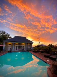 a house with a swimming pool in front of a sunset at Anchuca Historic Mansion & Inn in Vicksburg