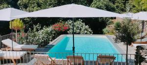 a swimming pool with a white umbrella and chairs and a pool at U Vechju Mulinu in Ortiporio
