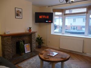 a living room with a tv and a fireplace at Bright spacious home, enclosed garden & parking in Hindlip