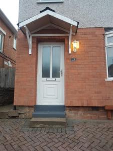 a brick house with a white door on it at Bright spacious home, enclosed garden & parking in Hindlip