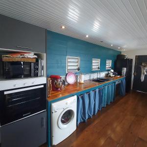 a kitchen with blue walls and a washer and dryer at Villa Fleurs Cacao in Trois-Rivières