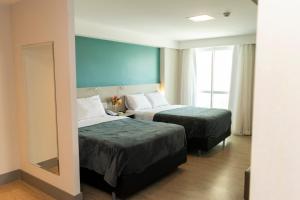 a hotel room with two beds and a mirror at 202 Flat Beira Mar Av Boa Viagem in Recife