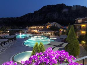 un complejo con piscina por la noche con flores púrpuras en Club Alla Turca en Dalyan