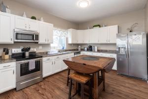 a kitchen with white cabinets and a wooden table at 5 Bedroom 3200 Square Foot House for Downtown Travelers in Indianapolis