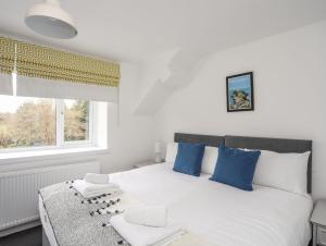a bedroom with a white bed with blue pillows and a window at Gorwel in Llanallgo