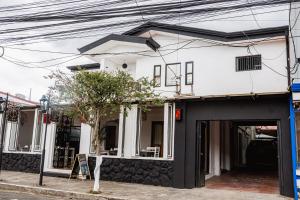 a white and black house with a tree in front of it at Hotel Luz de Luna Barrio Escalante in San José