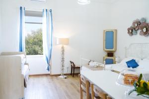 Habitación blanca con mesa, cama y ventana en Stella Marina Apartments, en Procida