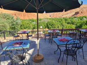 a patio with tables and chairs and an umbrella at Hotel Awayou in Bou Tharar