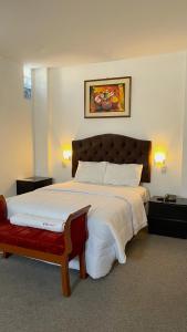 a bedroom with a large bed with a red bench at Hotel San Francisco de Paula Ayacucho in Ayacucho