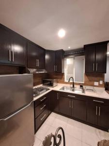 a kitchen with black cabinets and a stainless steel refrigerator at Departamento Orange in Ensenada