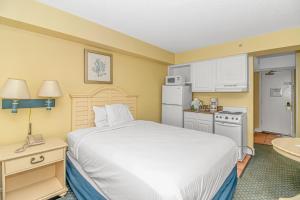 um quarto de hotel com uma cama e uma cozinha em Direct Oceanfront Sea Mist Resort 21101 em Myrtle Beach