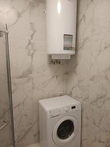 een witte wasmachine in een badkamer met marmeren muren bij Apartments Domovik Myru St. 11s/21 in Mukacheve