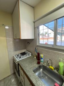 cocina con fregadero, fogones y ventana en House CÉNTRICA en Villa Carlos Paz